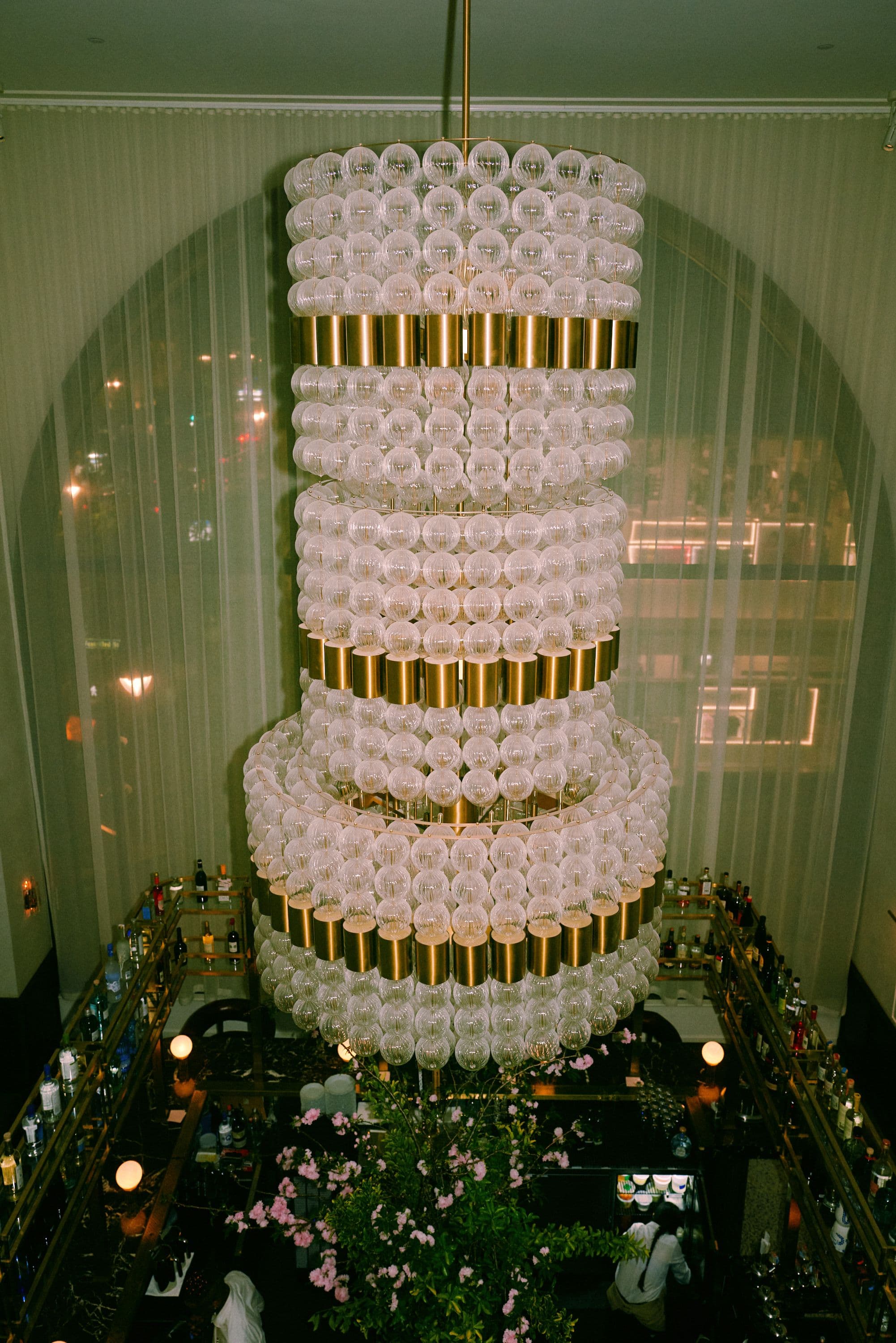 A view of Moss's corner bar Bar Babette with a 14 ft chandelier and monumental arched window that frames a view of Fifth Avenue in Midtown, New York City.